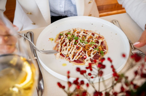 A plate features a dish in a white sauce garnished with decorative greens and crumble.