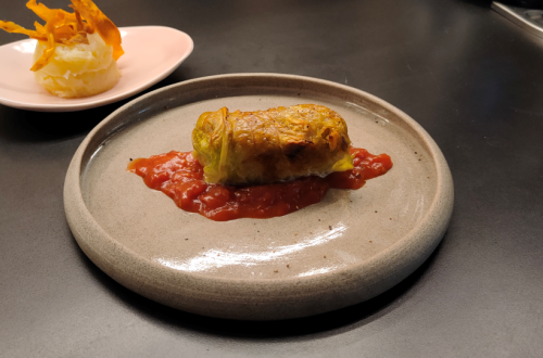 A plate features a wrap served on a tomato sauce.