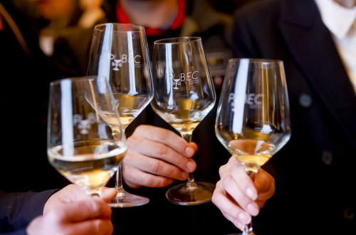 Holding four glasses of white wine in hands.