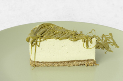 A slice of cake with white cream and a green filling shaped like spaghetti.