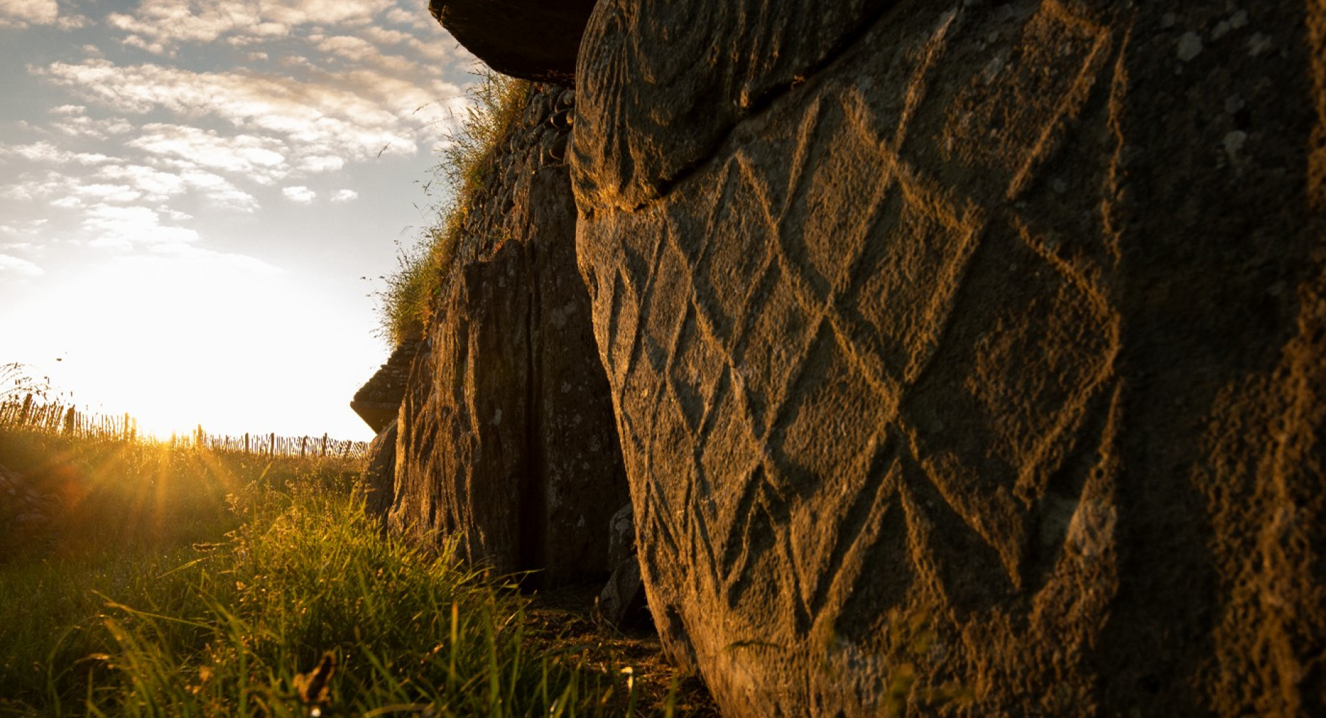 Obrobni kamen rjave barve s pogledom na s soncem obsijano zelenico.