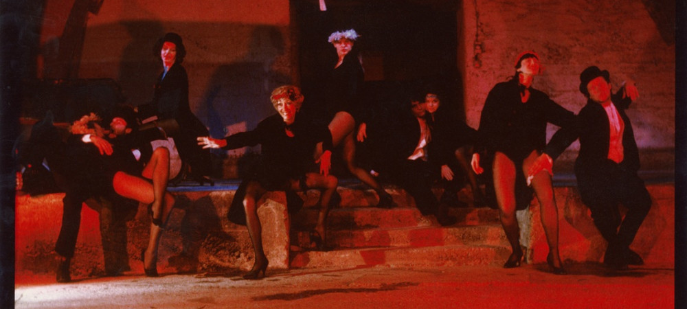 Vintage reddish photograph of actors in dark costumes.