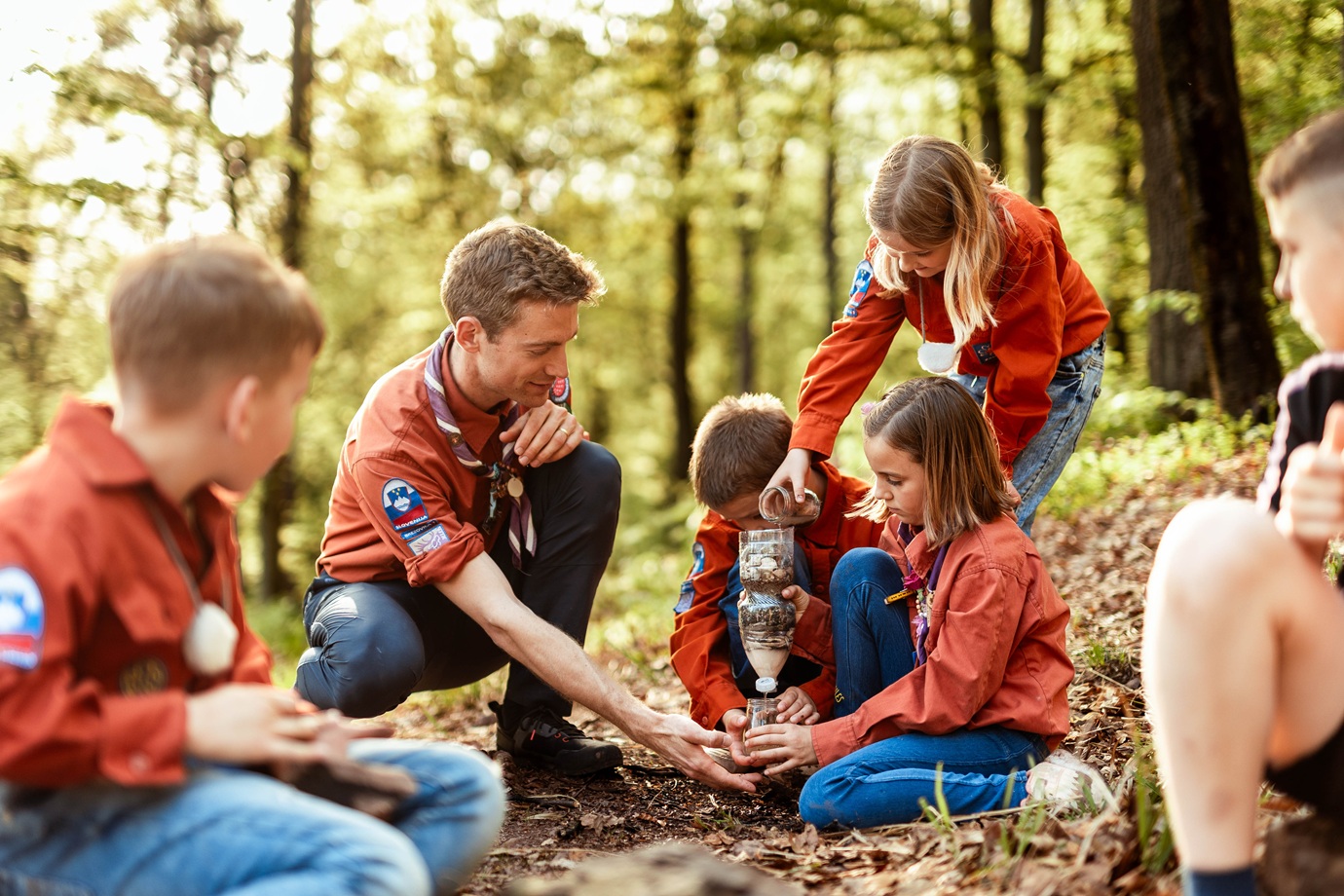Skavti v gozdu ustvarjajo ter se ucijo o zemlji in kamnih.