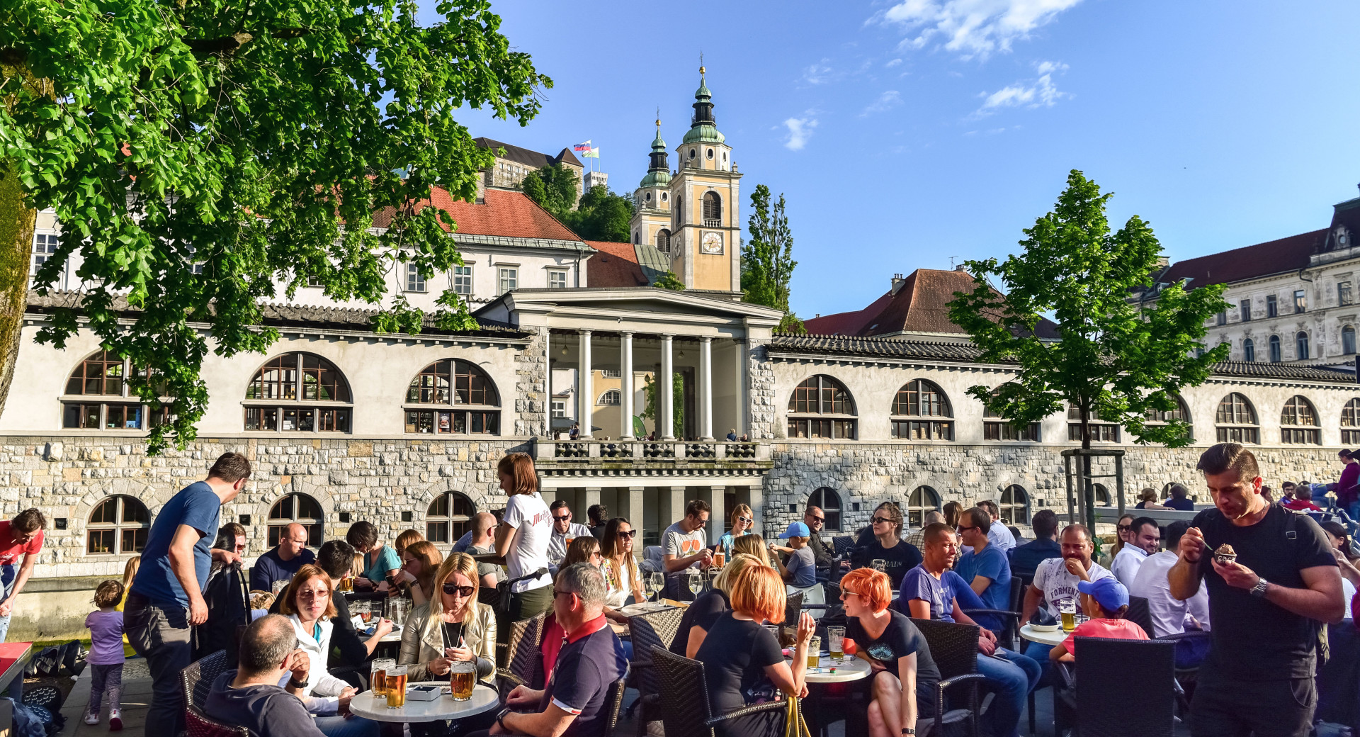 Ljudje posedajo na soncu na nabrezjih Ljubljanice.