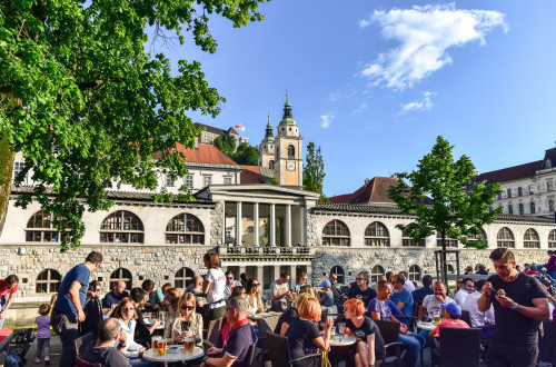 Ljudje posedajo na soncu na nabrezjih Ljubljanice.