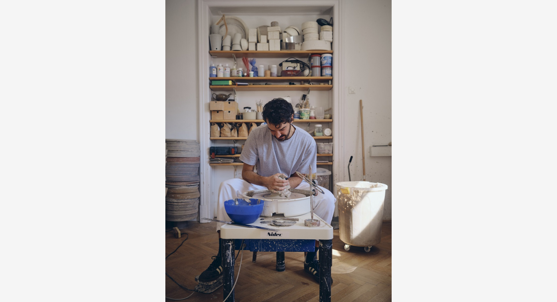 Moski sedi za glinenim vretenom in z rokami oblikuje izdelek.