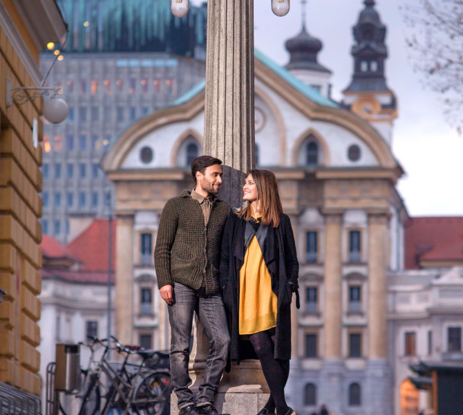 Par stoji ob stebru,  v ozadju cerkev.