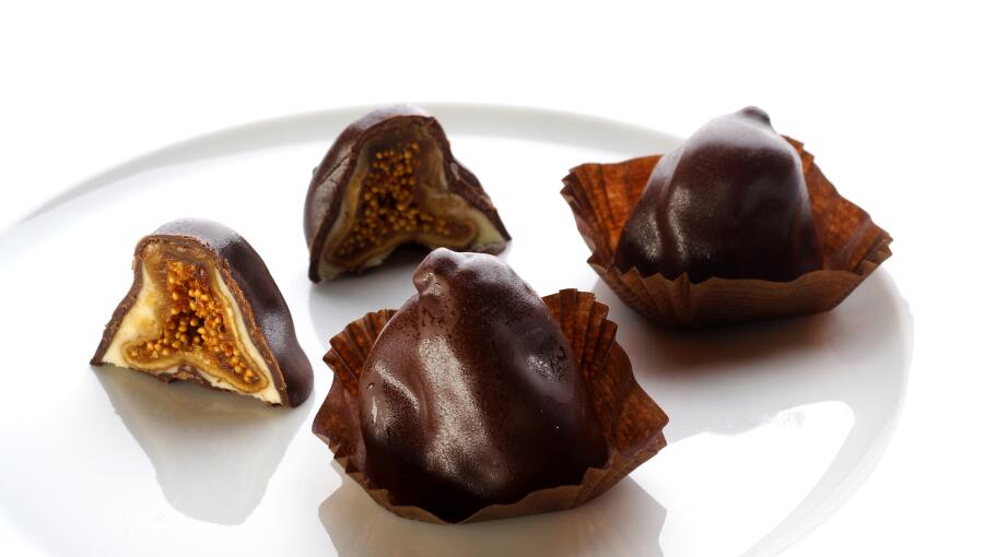 On the plate, there are figs coated in chocolate that look like small domes. The cross-section shows a rich interior.