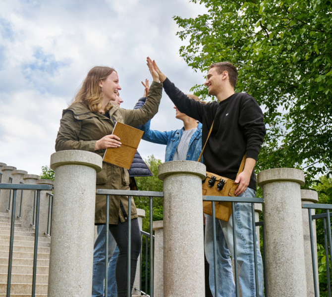 Dva para mladincev stojita na vznozju stopnic na gradu in si dajeta petko.