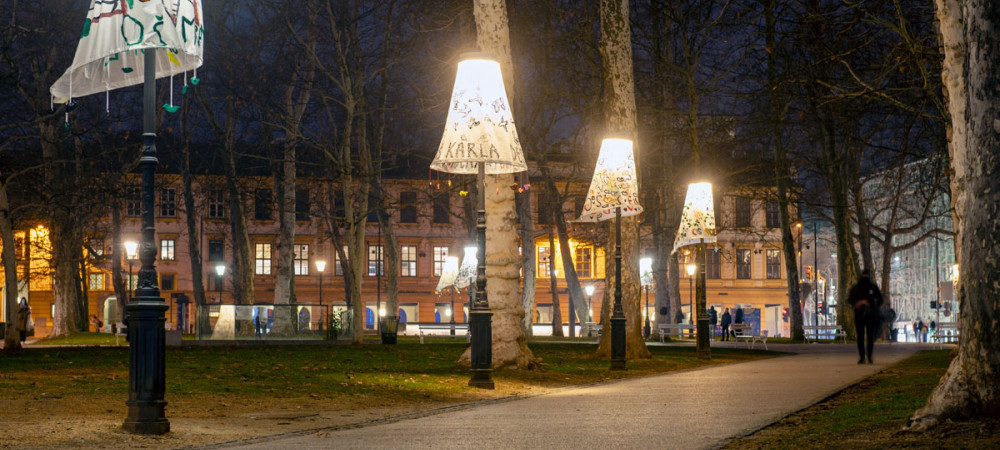 Štiri ulične svetilke v parku, pokrite z okrasnimi senčili.