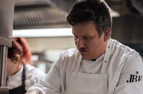 Chef v beli uniformi ureja kroznike s hrano.