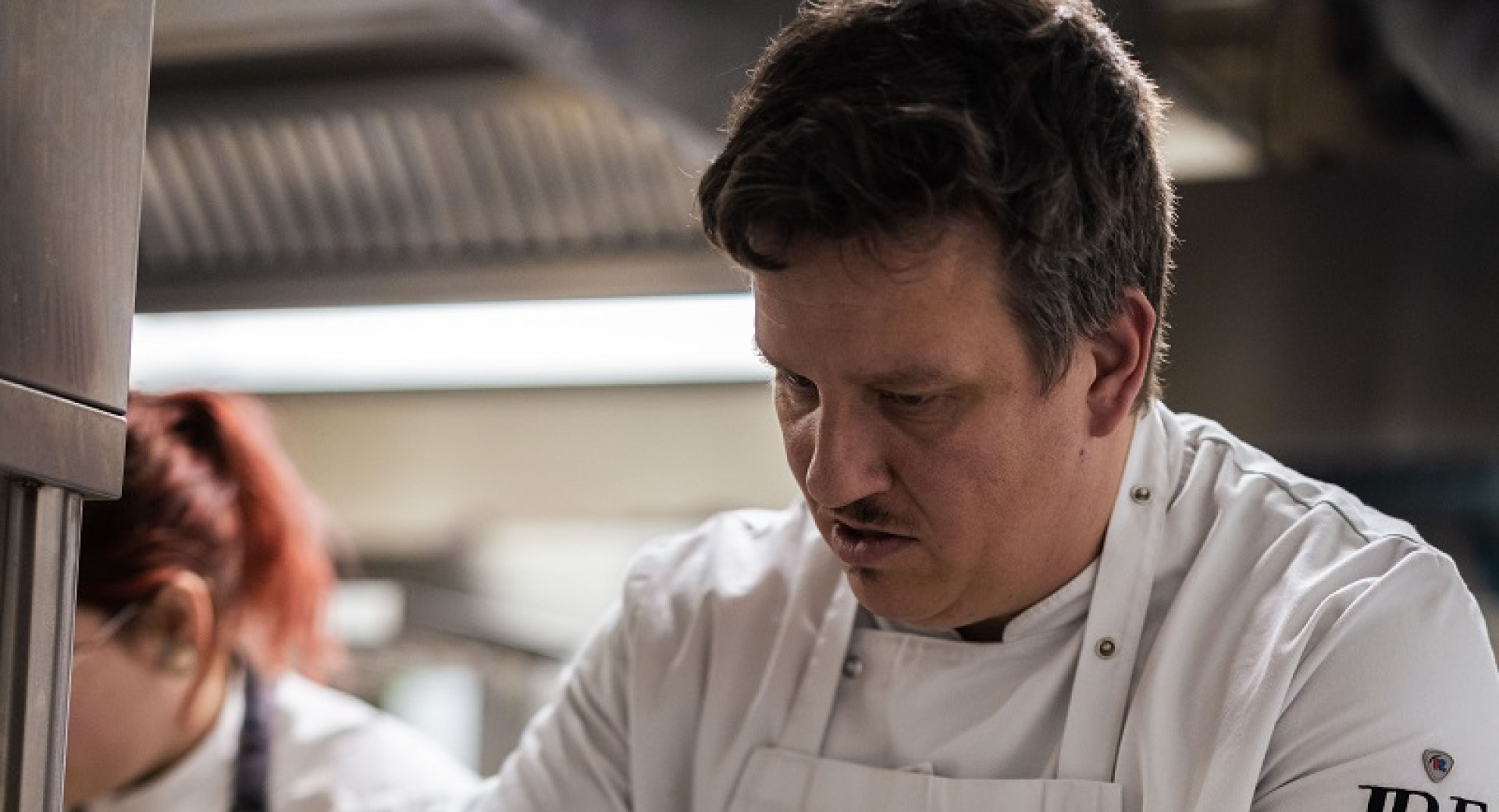 Chef v beli uniformi ureja kroznike s hrano.