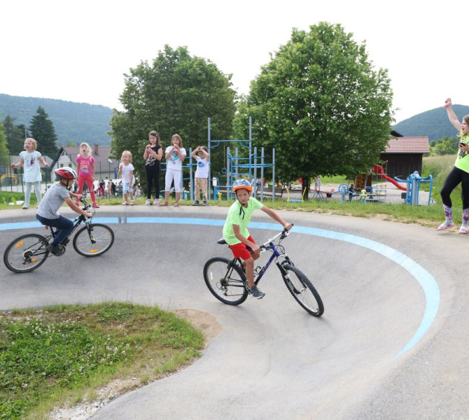Children cycle around the course while a group of enthusiastic observers watch behind them.