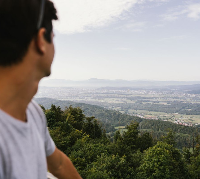 A man is facing the view of the settlements in the valley.
