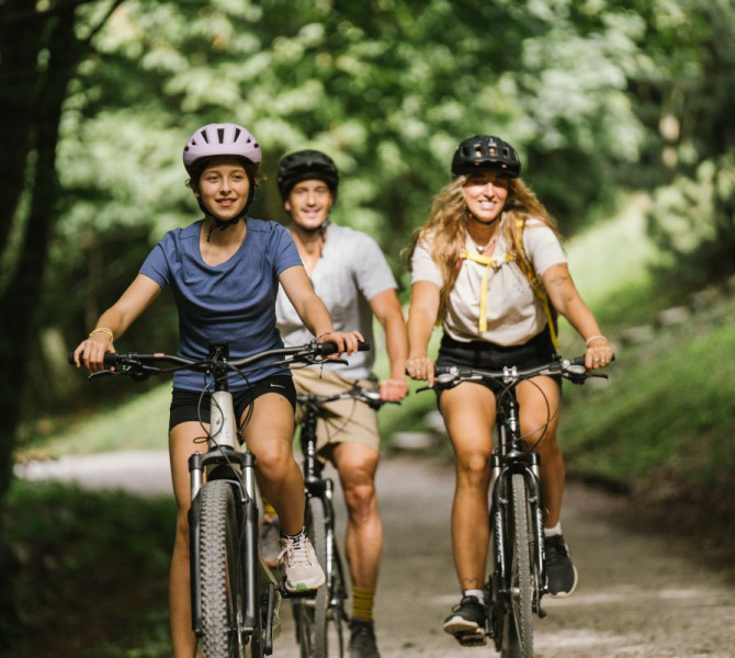 The family is cycling in the middle of nature.
