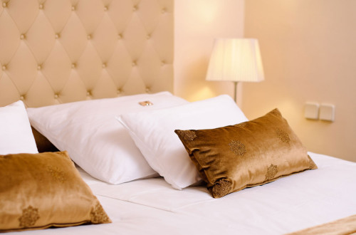 Bele in zlate blazine na posteljah v sobi hotel GH Union v Ljubljani.