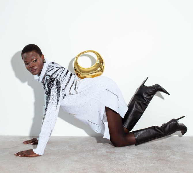 A woman in white shirt with a gold bag on her back kneeling on the floor.