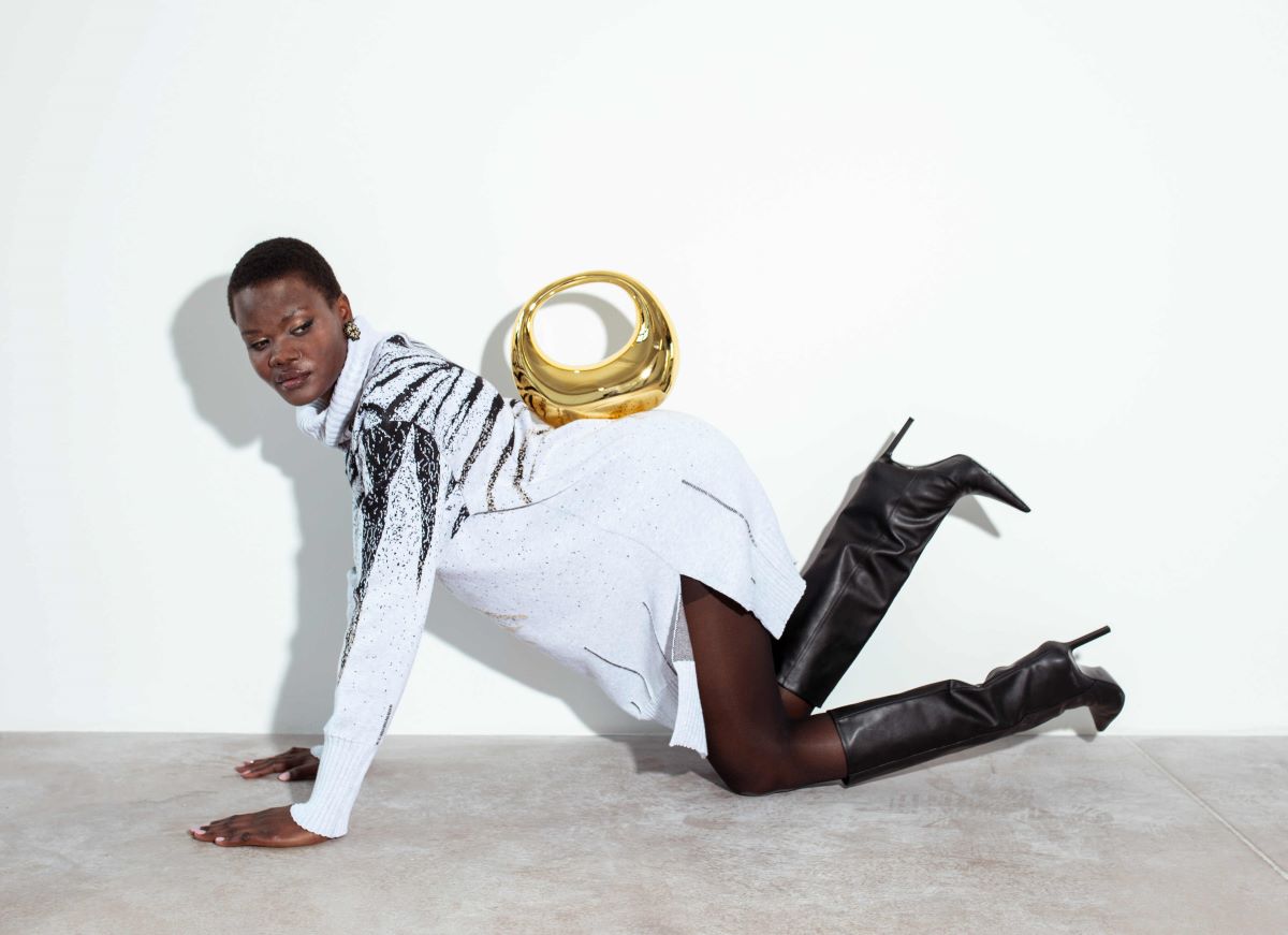 A woman in white shirt with a gold bag on her back kneeling on the floor.