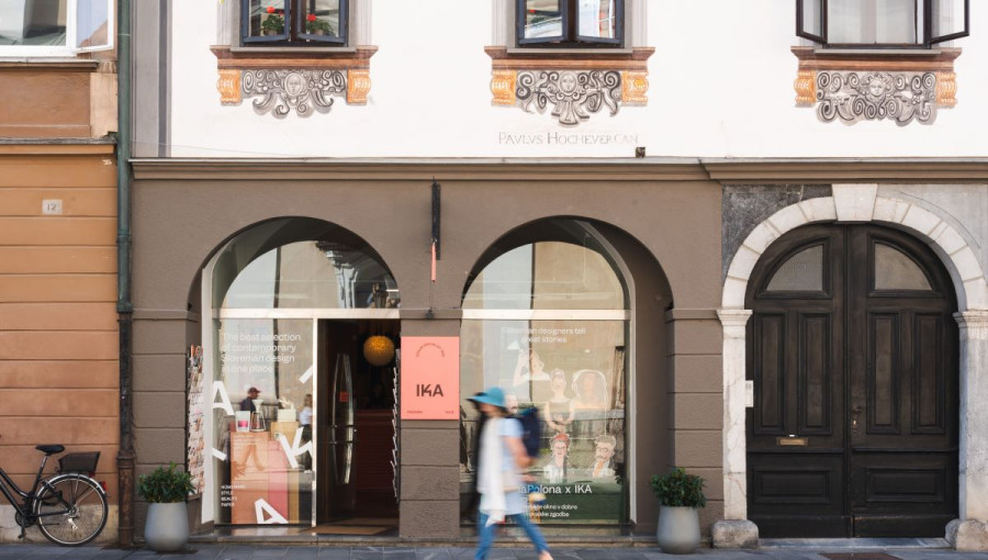 A woman walking past the white building with brown arches.