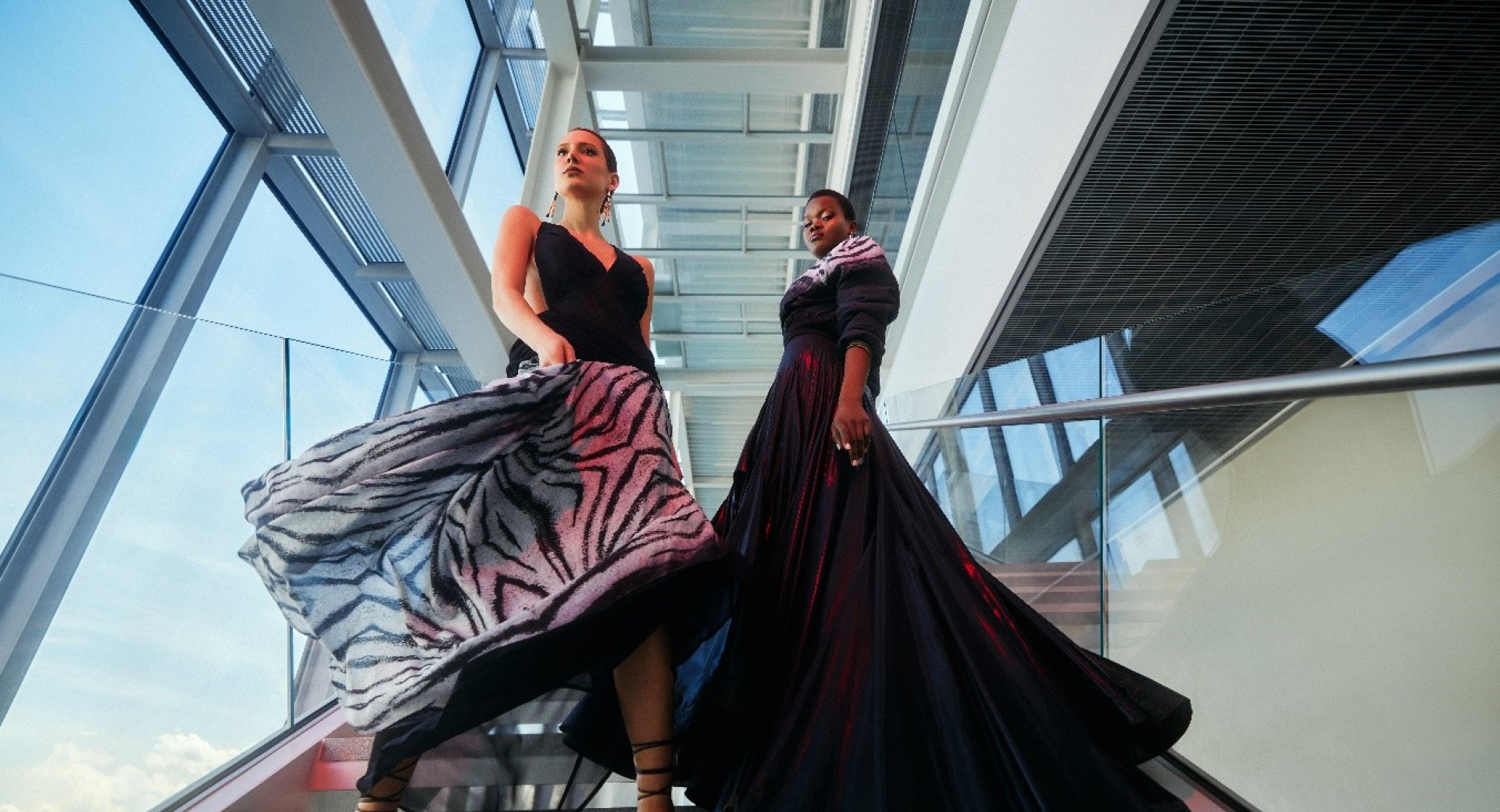 Two women in long black dresses on the stairs.