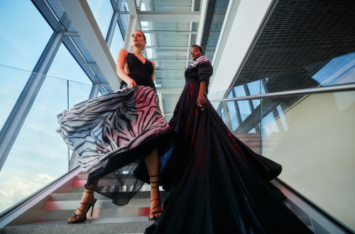 Two women in long black dresses on the stairs.