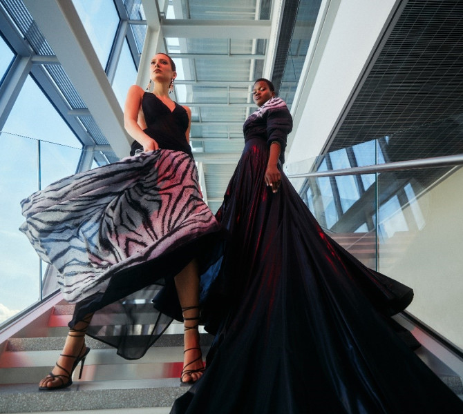 Two women in long black dresses on the stairs.