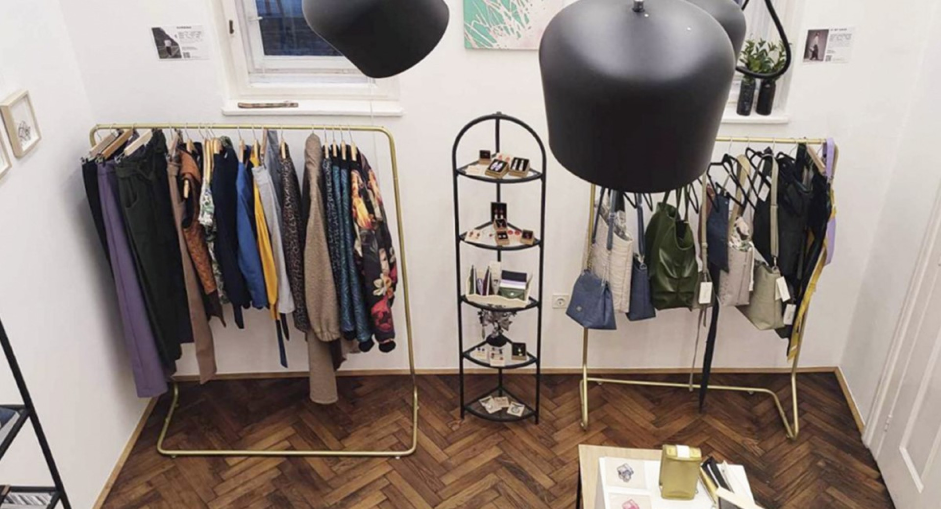Intérieur d'un magasin avec des vêtements, des sacs et des bijoux, éclairé par des lampes et disposé dans un style moderne.