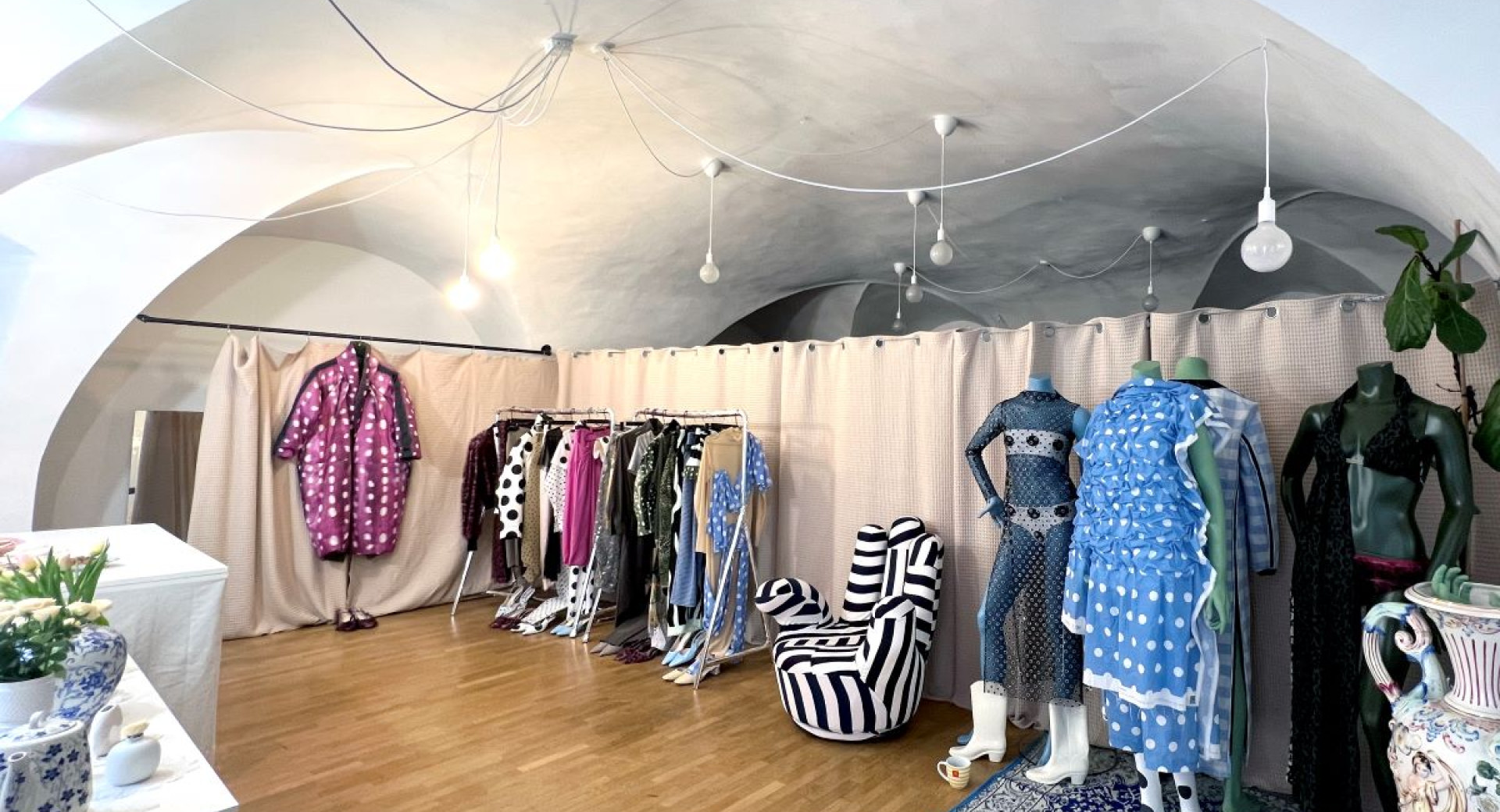 A fashion boutique with unique garments on display, featuring bold patterns, polka dots, and artistic decor.