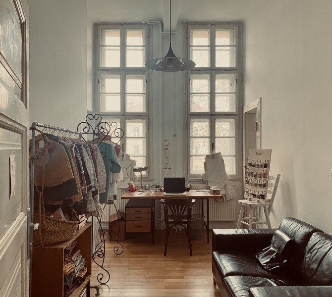 Open door to a room with a black couch and a clothing rack.
