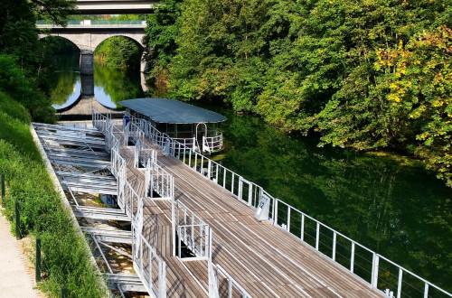 Pomol in turistična ladjica na Ljubljanici. V ozadju most.