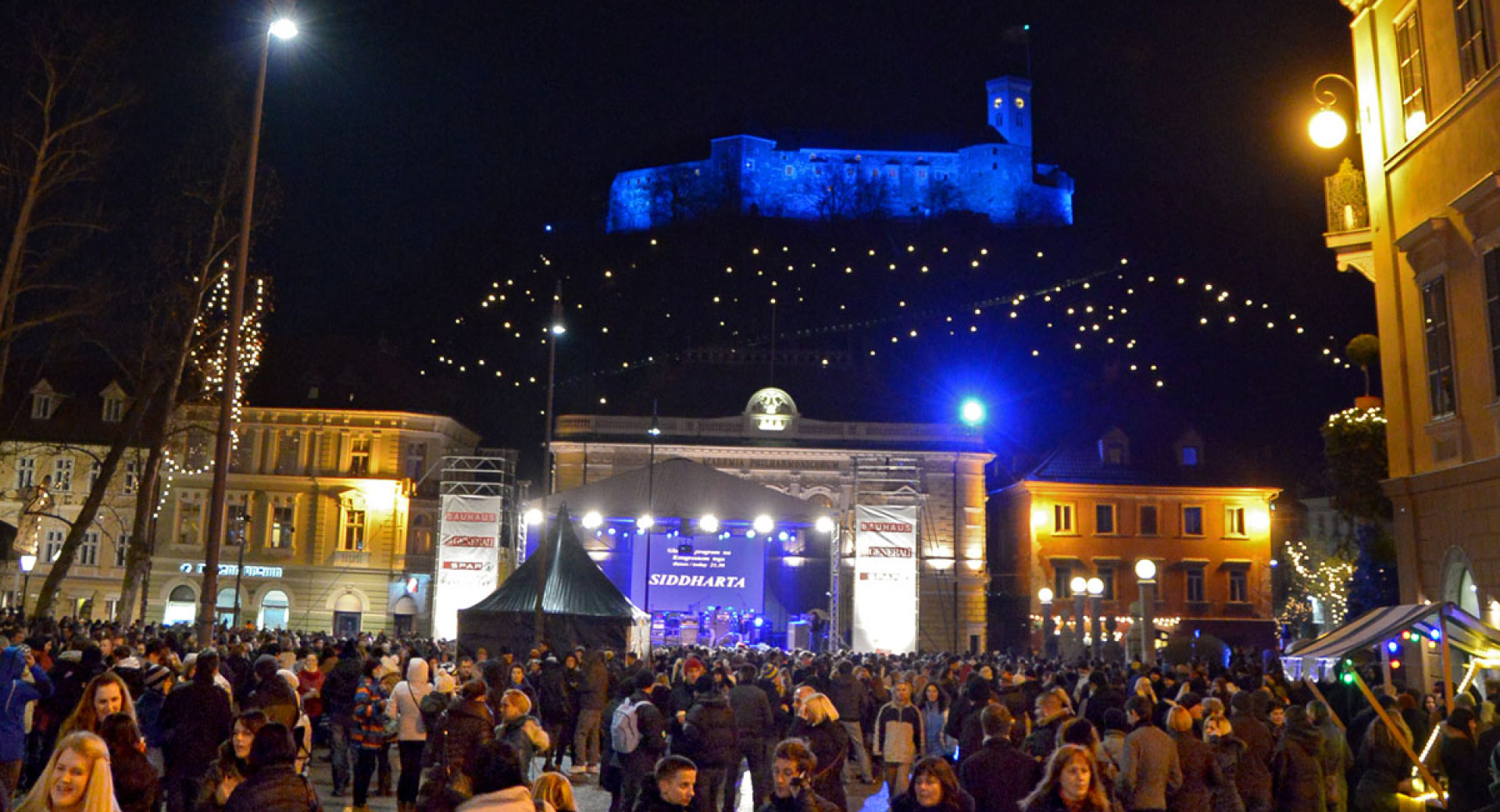 Večer na Kongresnem trgu v predbožičnem času. V ozadju osvetljen Ljubljanski grad. 