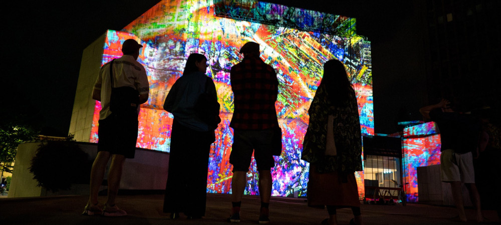 Silhouette of four people observing a light installation.