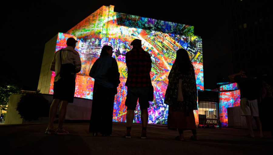 Silhouette of four people observing a light installation.