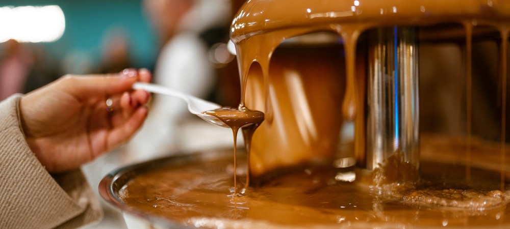 Zenska prislanja zlico k cokoladni fontani.