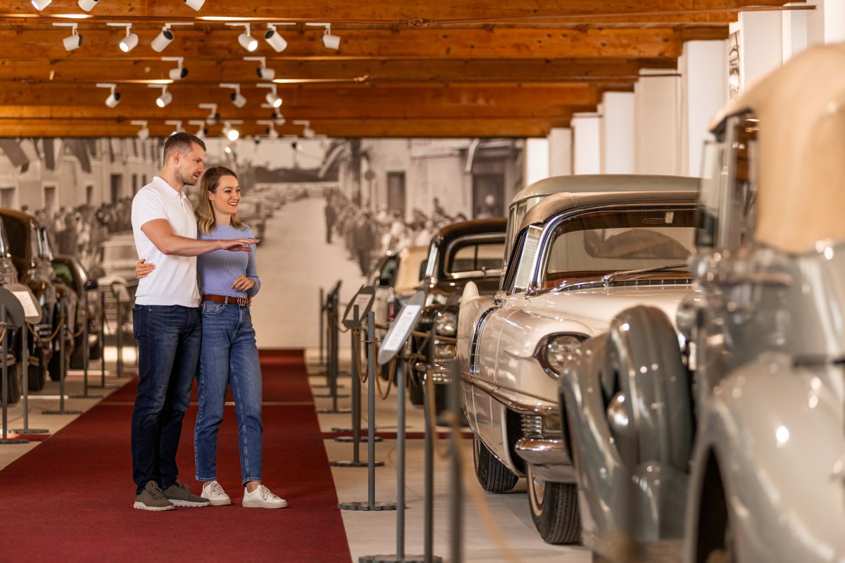 A couple is looking at vintage cars. Vintage cars in a museum.