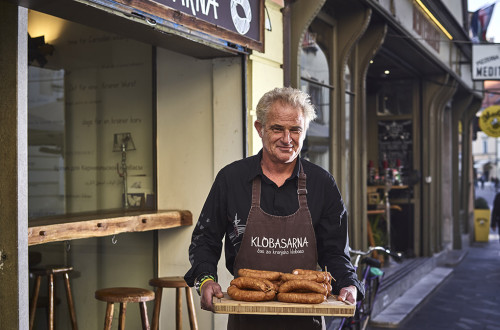 Gospod s klobasami na pladnju pred Klobasarno.