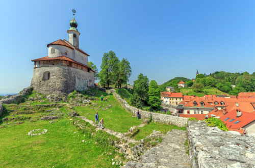 A church on a hill above the medieval town. Remains of the fortification wall are visible around the church.