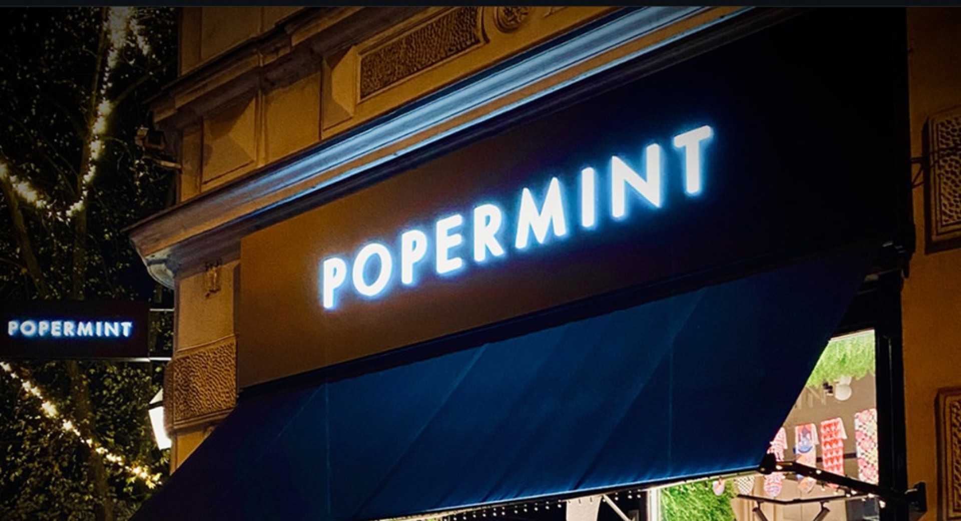 Osvetljena temna izlozba z napisom "Popermint".