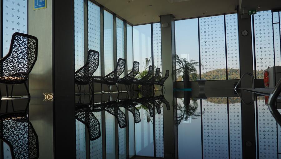 Floor-to-ceiling panoramic windows next to the pool, with lounge chairs in the foreground.