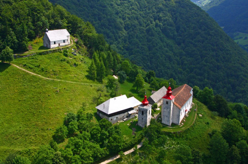 A photo of a church from above. Forests in the background.