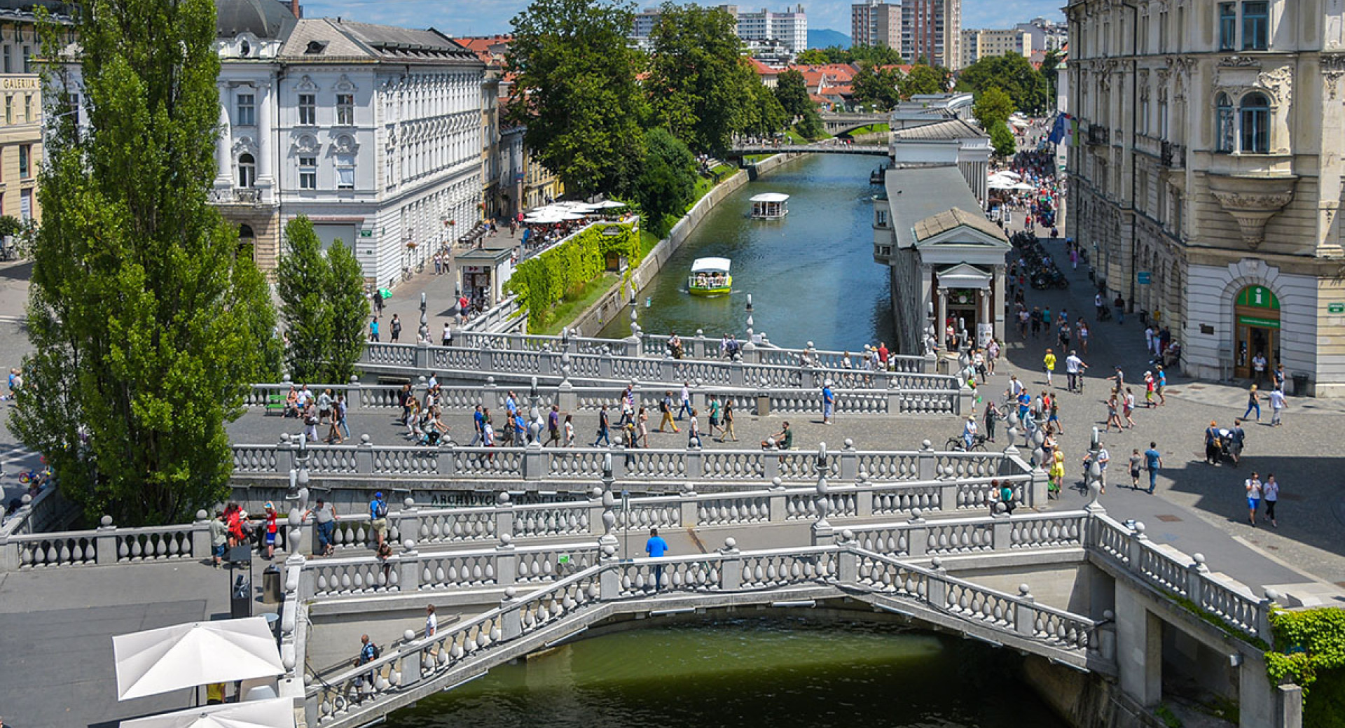 Tromostovje nad Ljubljanico, po kateri plujeta ladjici.