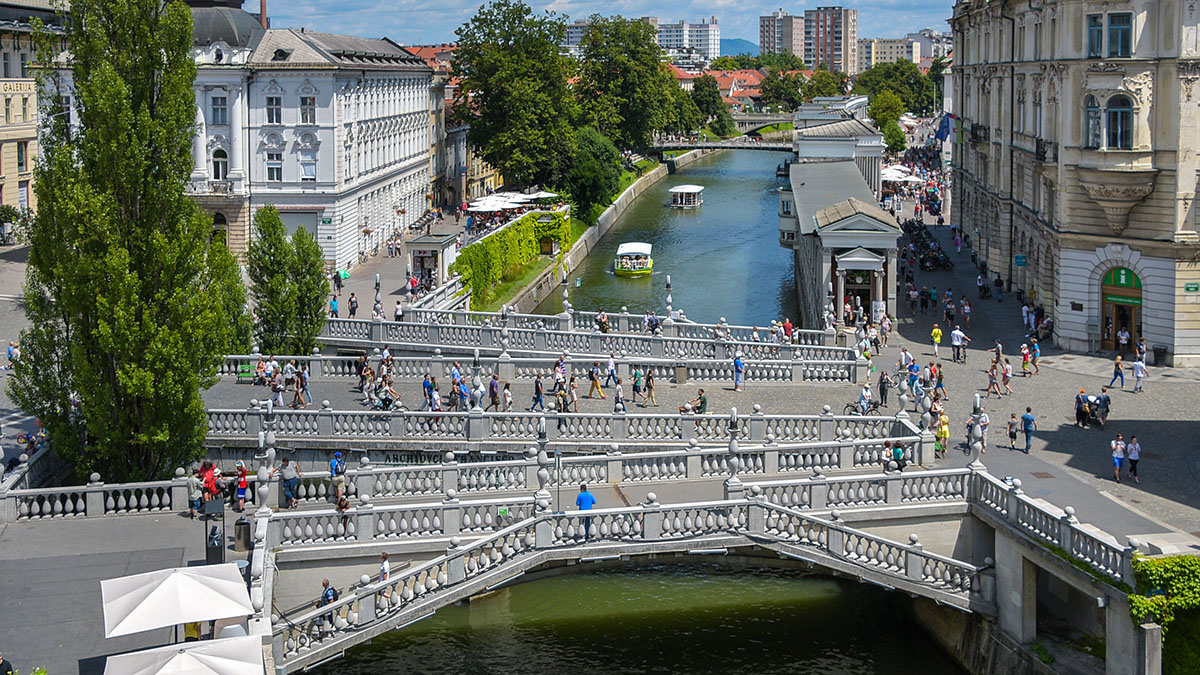 Tromostovje nad Ljubljanico, po kateri plujeta ladjici.