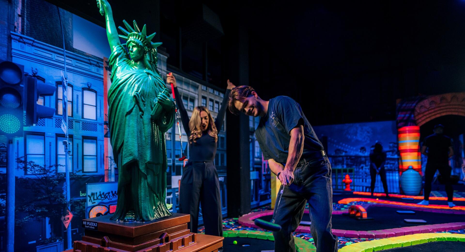 Un homme et une femme jouant au glow golf dans le noir.
