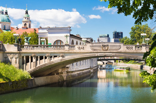 Zmajski most nad Ljubljanico, po kateri plujeta dve ladjici.