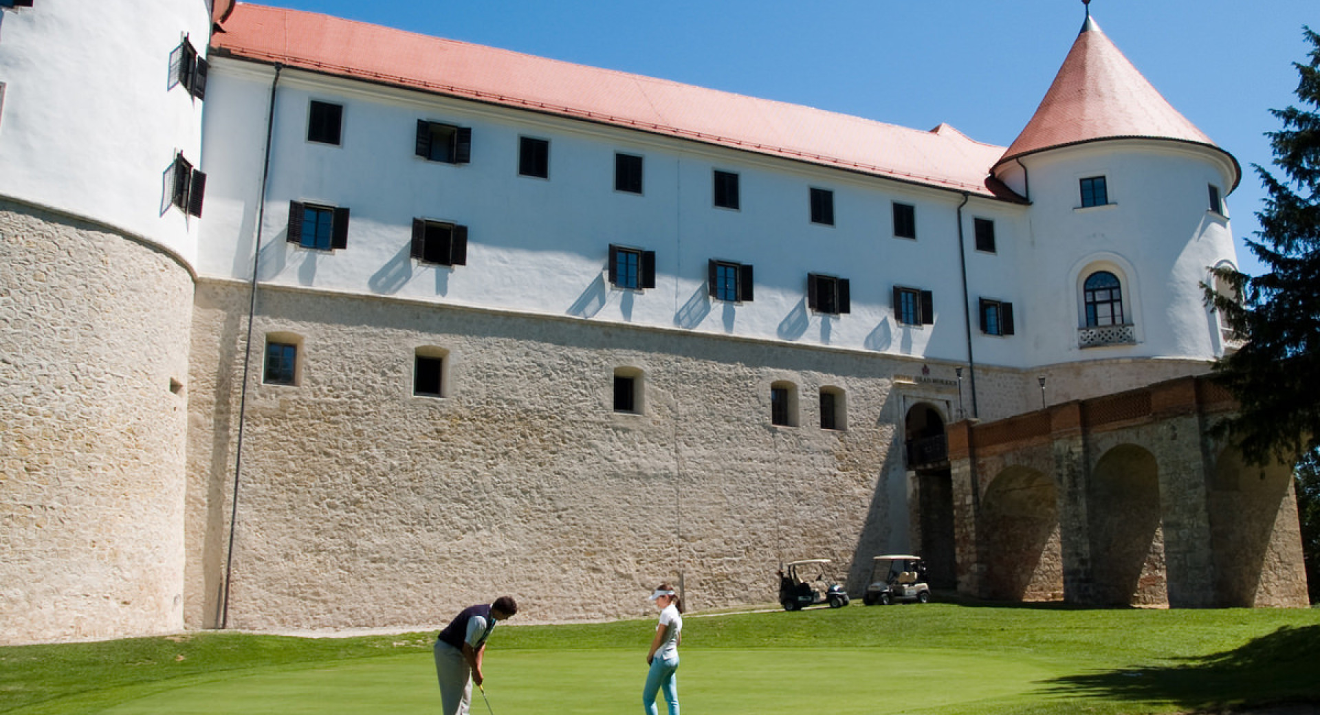 Golfista na igrišču. V ozadju grad Mokrice. 