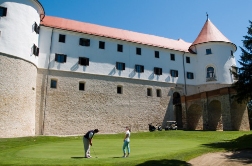 Golfista na igrišču. V ozadju grad Mokrice. 