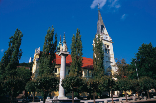 Levstikov trg s cerkvijo sv. Jakoba za drevesi.