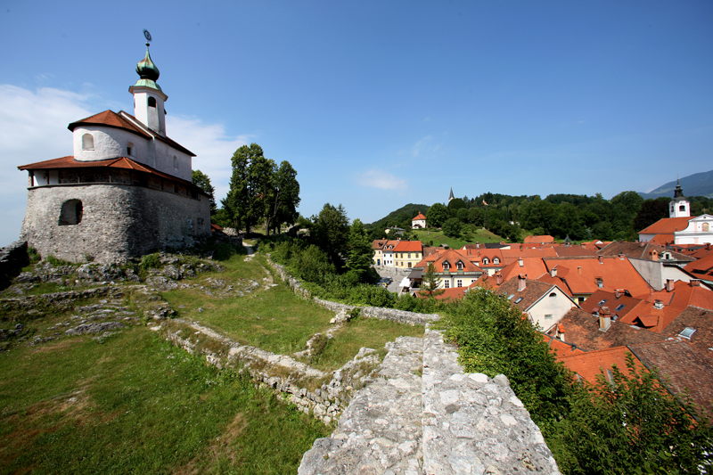 Levo kapelica, desno strehe vasi.