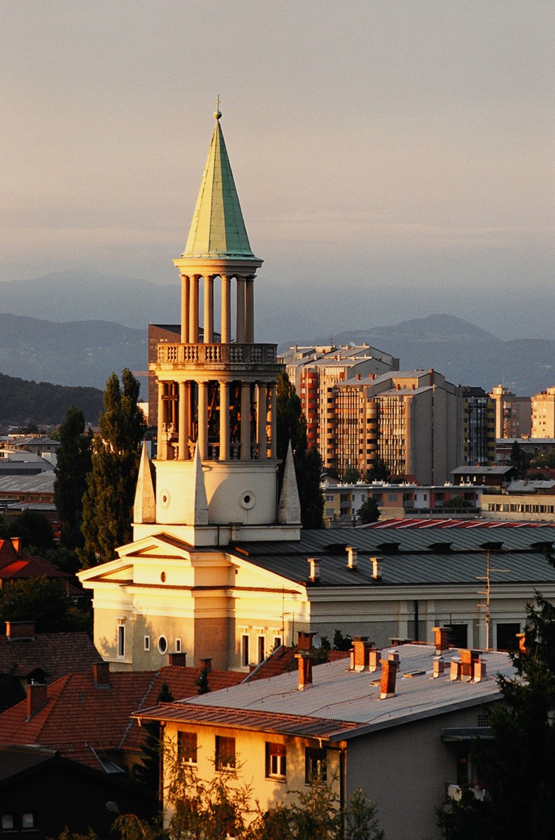 Panoramska slika cerkve s hribi v ozadju.