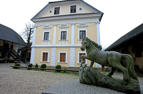 Zunanjost turistične kmetije. V ospredju je kip konja.